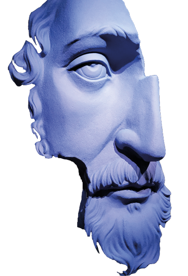 In einem abgedunkelten Museumsraum h ngt eine berlebensgro e, abstrakte Skulptur eines Gesichts von der Decke. Die Skulptur zeigt nur die linke H lfte eines m nnlichen Gesichts mit betontem Auge, Nase, Bart und lockigem Haar. Die gesamte Oberfl che ist in einem auff lligen, matten Blau eingef rbt. Der Kopf wirkt monumental und surreal. Hinter der Skulptur h ngt ein Vorhang. Im Hintergrund erkennt man eine beschriftete Tafel an der Wand sowie eine leuchtende Wandgrafik in gedeckten Farben. Die Atmosph re des Raumes ist ruhig und modern, mit gezielter Beleuchtung, die die Skulptur betont.