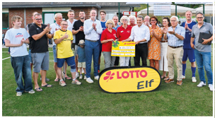 Das Bild zeigt eine gro e Gruppe von Menschen auf einem Fu ballplatz, die sich zu einem feierlichen Anlass versammelt haben. Im Mittelpunkt steht eine symbolische Spendenscheck- bergabe in H he von 16.000 Euro von LOTTO Rheinland-Pfalz (erkennbar am gro en gelben Scheck und dem „LOTTO Elf“-Banner im Vordergrund).   Die Personen wirken fr hlich und stolz, viele klatschen Beifall. Einige tragen Fu balltrikots, andere sind in Alltagskleidung – ein Mix aus Spielern, Veranstaltern, G sten und Vereinsvertretern. Im Hintergrund sieht man ein Vereinsgeb ude, Banner von Sponsoren und Zuschauer auf B nken.    Die Szene strahlt Gemeinschaft, Engagement und Unterst tzung f r einen guten Zweck aus.