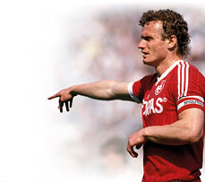 Auf dem Bild ist ein ehemaliger Fu ballspieler zu sehen, der ein rotes Trikot tr gt. Es handelt sich um Hans-Peter Briegel, genannt „Die Walz von der Pfalz“. Er war ein bekannter deutscher Spieler. Briegel zeigt mit dem rechten Arm zur Seite – vermutlich w hrend eines Spiels. Das Foto wirkt historisch, aus den 1980er Jahren.