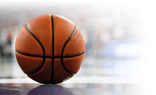 Ein klassischer Basketball liegt auf einem gl nzenden Hallenboden. Man sieht, wie sich der Ball darin spiegelt.