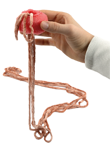 Auf dem Bild ist eine Hand zu sehen, die ein St ck Poolnudel h lt, rot und schwammartigen. Aus diesem Objekt h ngen mehrere lange, orangene Wollf den herab. Die Person tr gt einen hellen, lang rmeligen Pullover.