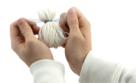 Auf dem Bild sind zwei H nde zu sehen, die ein kleines B ndel aus wei er Wolle halten. Die Wolle ist zu einer Kugelform gewickelt und im oberen Bereich mit einem schmalen, hellen Band (vermutlich aus Organza oder Satin) zusammengebunden. Die Person tr gt einen wei en, lang rmligen Pullover. 