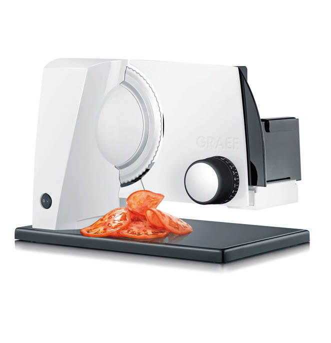 Das Bild zeigt einen modernen Allesschneider der Marke Graef. Es handelt sich um ein elektrisch betriebenes K chenger t mit einem glatten, wei en Geh use und einem auff llig gro en, runden, gezackten Schneidemesser aus Metall auf der linken Seite. Vor dem Schneidemesser liegen mehrere gleichm ig d nn geschnittene Tomatenscheiben auf einer dunklen Ablagefl che, die zur Maschine geh rt. Auf der rechten Seite des Ger ts befindet sich ein gro er schwarzer Drehregler mit einer silbernen Mitte, vermutlich zur Einstellung der Schnittst rke. Dahinter ist ein schwarzer Schlitten oder Halter zu sehen, in den das zu schneidende Lebensmittel eingespannt wird. Das Ger t steht auf einer gl nzenden, dunklen Unterlage. Der Hintergrund ist reinwei , wodurch das Ger t klar im Fokus steht.