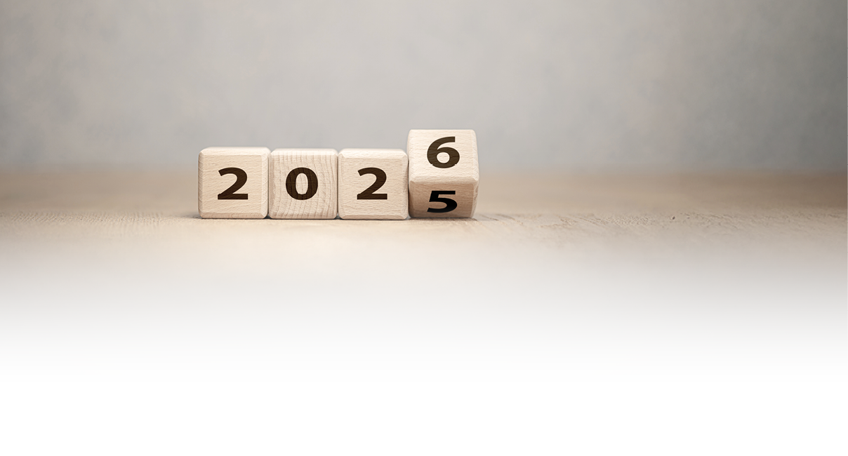 Auf dem Bild sind vier Holzkl tze mit aufgedruckten Ziffern zu sehen. Drei Kl tze zeigen die Zahl „202“, der vierte Klotz ist drehbar und zeigt die Ziffern „5“ und „6“. Aktuell ist die „6“ sichtbar, w hrend die „5“ noch teilweise erkennbar ist. Die Darstellung symbolisiert den Jahreswechsel von 2025 zu 2026.