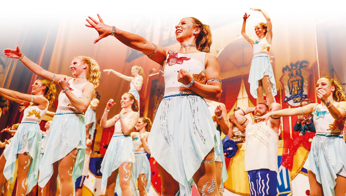 Mehrere Frauen in wei en Kost men mit blauen und goldenen Verzierungen tanzen auf einer B hne bei der Lotto-Benefizfastnachtssitzung in Mainz.