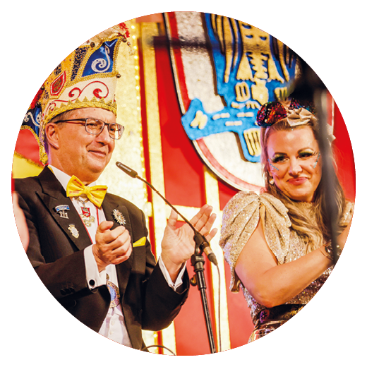 Zwei Personen im Elferrat der Lotto-Benefizfastnachtssitzung in Mainz, eine tr gt eine bunte Narrenkappe und Fliege, die andere ein glitzerndes Kost m mit Haarschmuck.