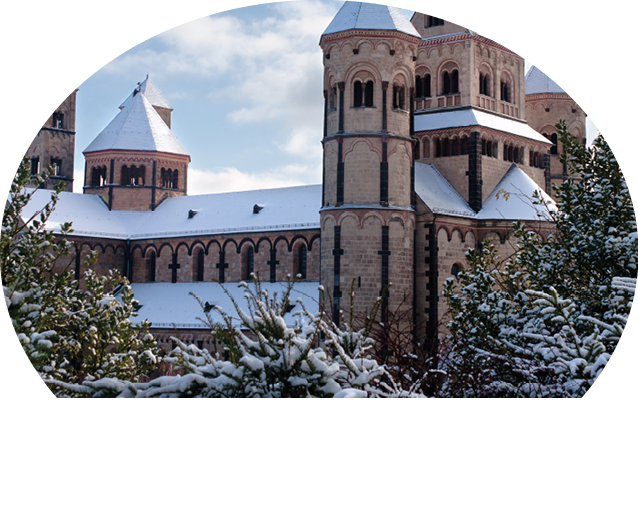 Romanische Kirche mit mehreren T rmen und schneebedecktem Dach umgeben von schneebedeckten Nadelb umen