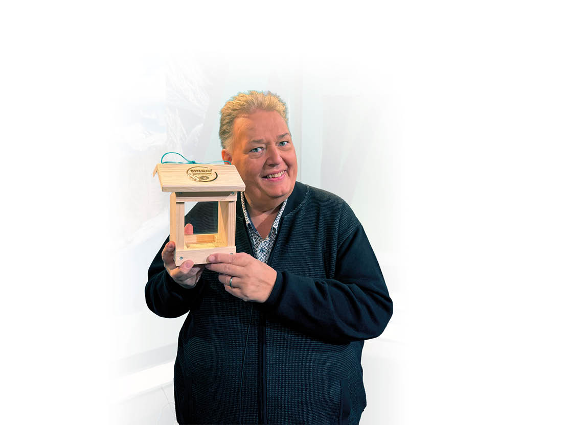 Person h lt ein kleines h lzernes Vogelhaus mit einem Dach und einem offenen Fach