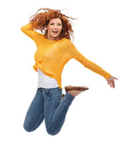 Frau mit freudigem Gesichtsausdruck springt mit nach hinten angwinkelten Beinen vor Freude in die Luft