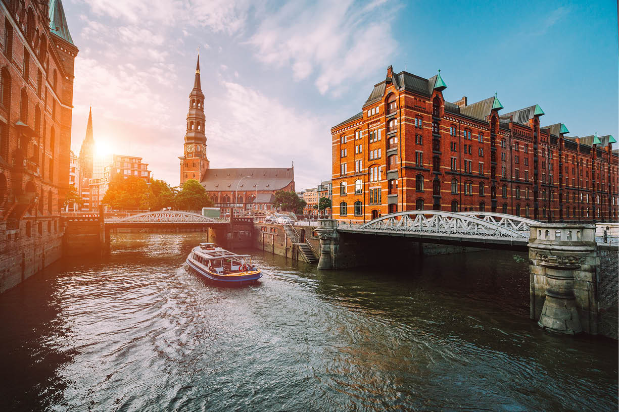 Blick auf die Speicherstadt in Hamburg mit einem Boot auf dem Wasser und historischen Backsteingeb uden bei Sonnenuntergang