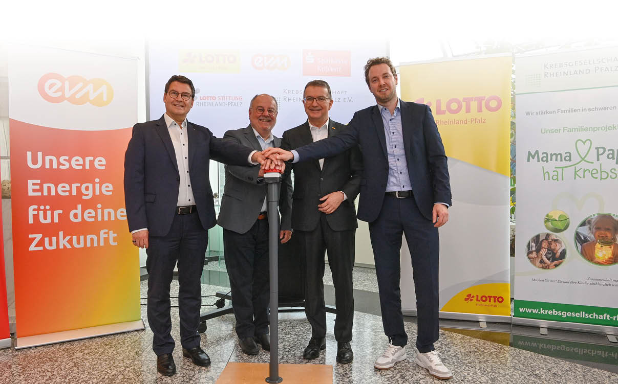 Vier M nner in Anz gen stehen um eine Stele und halten jeweils eine Hand auf der Spitze selbiger.