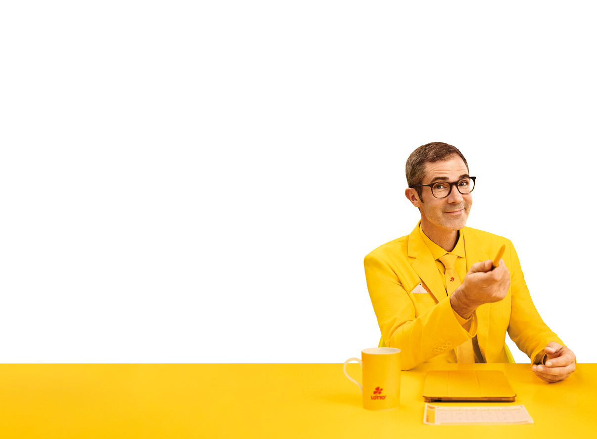 Das Bild zeigt einen sitzenden Mann vor einem einfarbig gelben Hintergrund. Er tr gt ein komplett gelbes Outfit, bestehend aus Sakko, Hemd und Krawatte, und sitzt an einem ebenfalls gelben Tisch.   Der Mann hat kurze dunkle Haare, tr gt eine Brille mit dunklem Rahmen und l chelt freundlich. Mit seiner rechten Hand zeigt er leicht nach vorne, als w rde er jemanden ansprechen oder etwas erkl ren. In der linken Hand h lt er einen Stift.    Auf dem Tisch vor ihm liegen ein gelbes Notizbuch oder Block sowie ein Lottoschein. Links steht eine gelbe Tasse mit einem kleinen roten LOTTO-Logo.    Die gesamte Szene ist farblich stark auf Gelb abgestimmt, wodurch ein auff lliger, moderner und leicht humorvoller Eindruck entsteht.