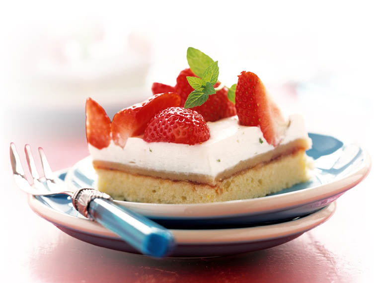 Das Bild zeigt ein St ck Erdbeerkuchen auf einem kleinen Teller. Der Kuchen besteht aus einem hellen, luftigen Boden, darauf eine cremige, wei e Schicht und oben mehrere frische, rote Erdbeeren. Die Erdbeeren sind teils halbiert und gl nzen leicht. In der Mitte liegt ein kleiner gr ner Minzzweig als Dekoration.  Der Teller steht auf einem roten Tisch. Daneben liegen eine Gabel und ein Messer mit blauem Griff.  Im Hintergrund ist ein weiterer Teller mit einem zweiten St ck Kuchen zu sehen, jedoch unscharf.  Die Lichtstimmung ist hell und freundlich, wodurch die Farben besonders frisch wirken.  Gesamteindruck:  Das Bild wirkt appetitlich und sommerlich – ein frisches Dessert mit fruchtiger Note.  
