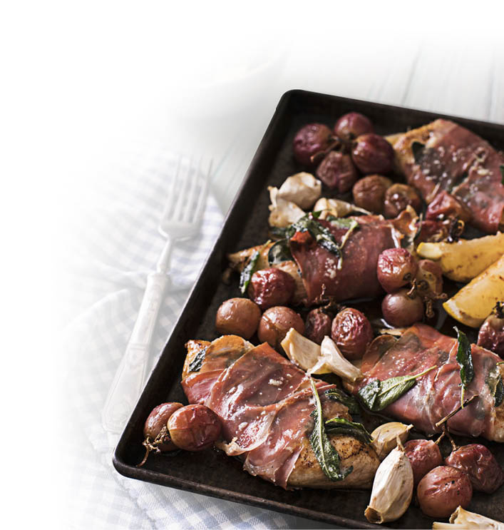 Auf einem Backblech liegen gebratene H hnchenbrustfilets, umgeben von roten Trauben, Knoblauchzehen, Salbeibl ttern und Kartoffelspalten. Beschreibung von KI generiert