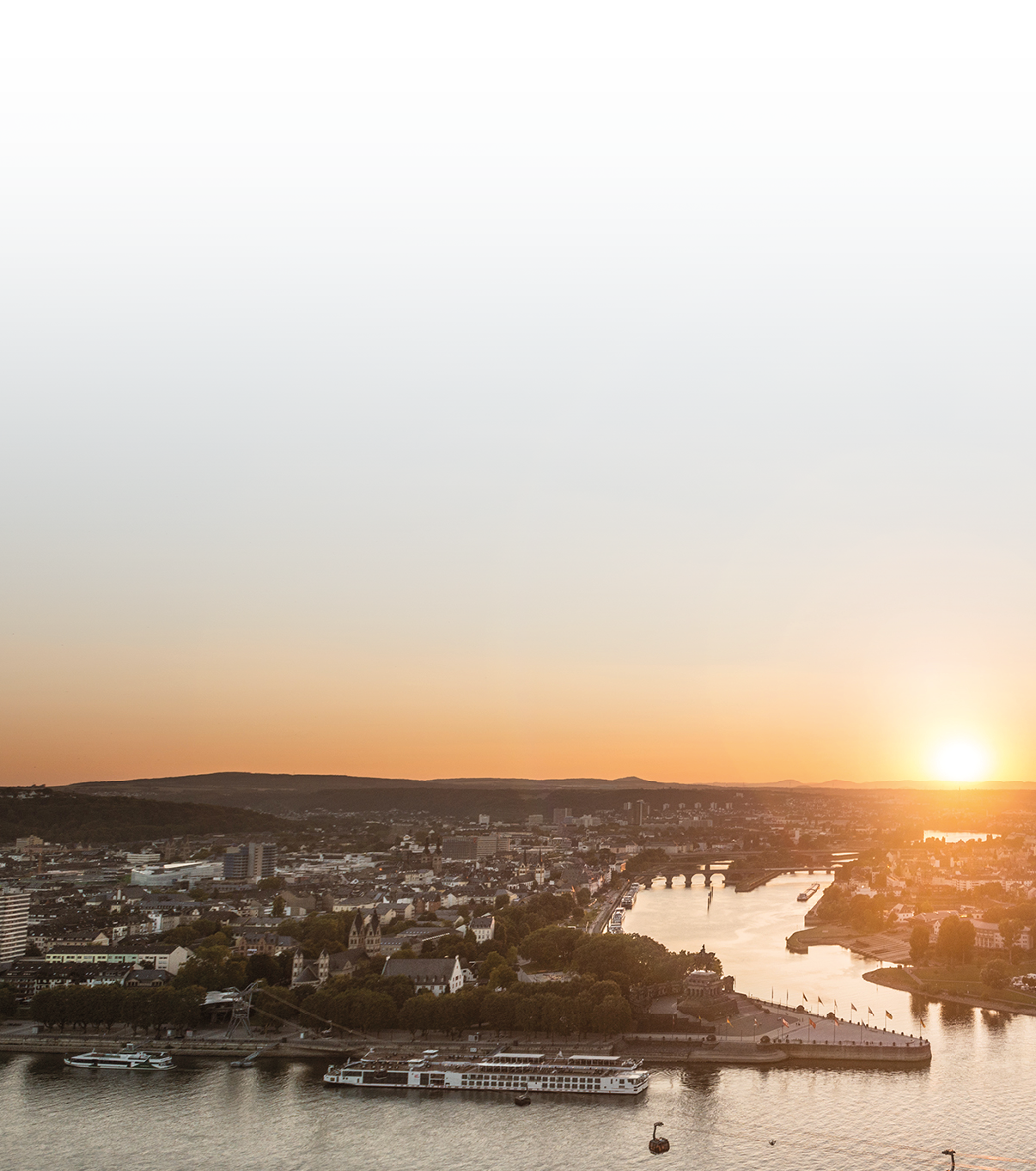 Sonnenuntergang ber einer Stadt mit einem Fluss, auf dem Seilbahnkabinen  ber das Wasser fahren.  Beschreibung von KI generiert