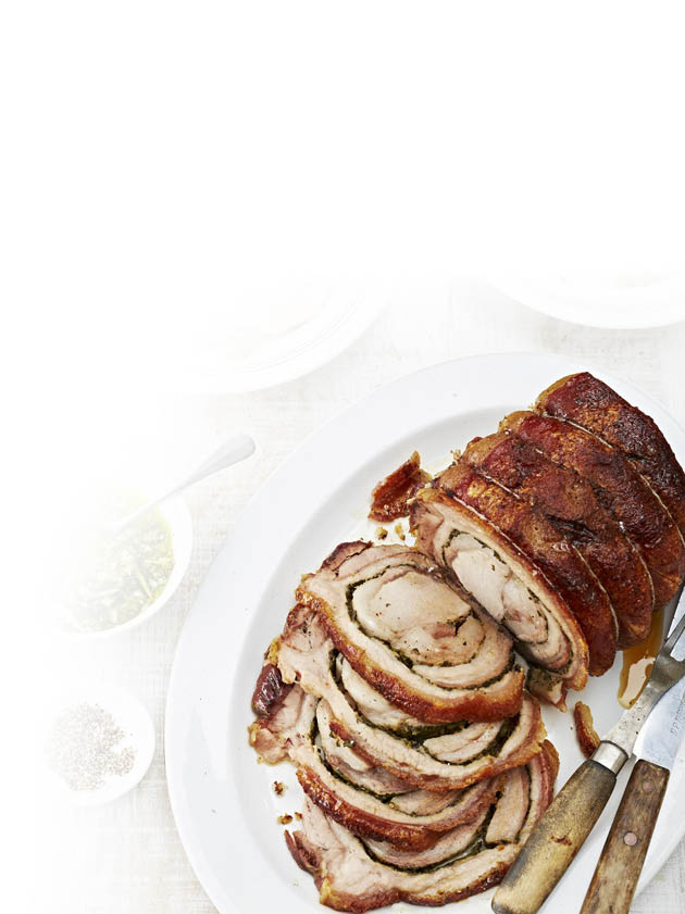 Auf einem wei en Teller liegt ein aufgeschnittener, gerollter Braten mit knuspriger Kruste, daneben liegen ein Messer und eine Gabel mit Holzgriffen. Beschreibung von KI generiert
