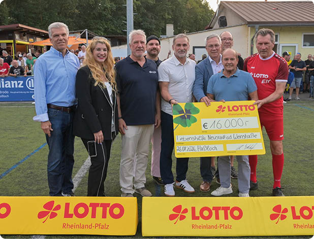 Eine Gruppe von acht Personen steht auf einem Sportplatz und h lt gemeinsam einen gro en symbolischen Scheck mit einer Spendensumme, umgeben von Werbebannern der Lotto Rheinland-Pfalz. Beschreibung von KI generiert