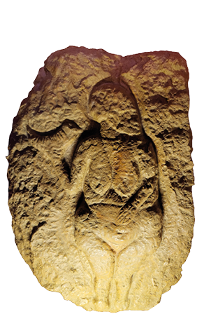 Eine in Stein gemei elte, stilisierte Figur mit betonten K rpermerkmalen sitzt mit angewinkelten Beinen und einer Hand auf dem Bauch. Beschreibung von KI generiert