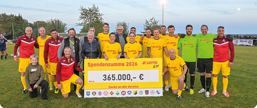 Eine Gruppe von Erwachsenen in Sportkleidung steht auf einem Fu ballfeld und h lt ein gro es Spendenscheck mit einer hohen Summe. Beschreibung von KI generiert