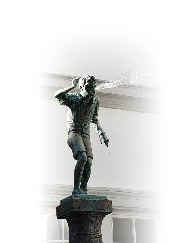 Eine Bronzestatue einer Person in kurzer Kleidung steht auf einem Sockel und spr ht Wasser aus dem Mund. Beschreibung von KI generiert
