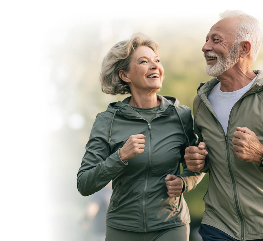 Zwei Senioren in Sportkleidung joggen gemeinsam drau en in einem gr nen Park und l cheln sich dabei an. Beschreibung von KI generiert