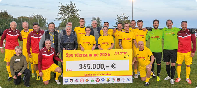 Eine Gruppe von Erwachsenen in Sportkleidung steht auf einem Fu ballfeld und h lt ein gro es Schild mit einer Spendensumme. Beschreibung von KI generiert