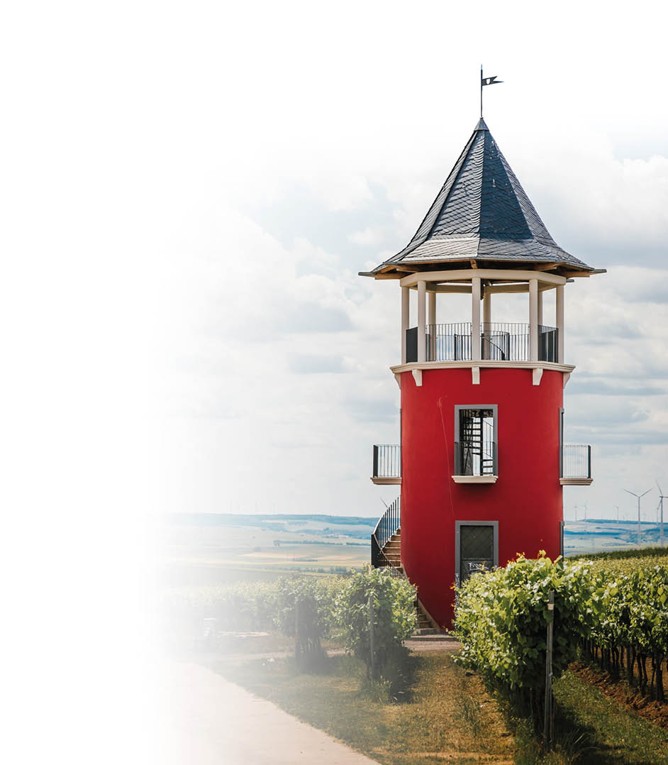 Ein roter Aussichtsturm mit spitzem Dach steht inmitten eines Weinbergs unter einem bew lkten Himmel. Beschreibung von KI generiert